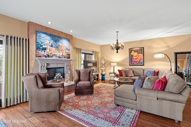 living area with recessed lighting, wood-type flooring, a notable chandelier, and a fireplace