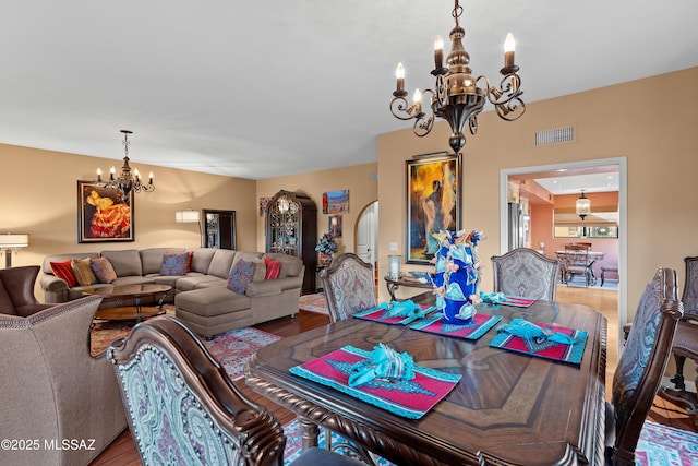 dining room featuring visible vents, a chandelier, arched walkways, and wood finished floors