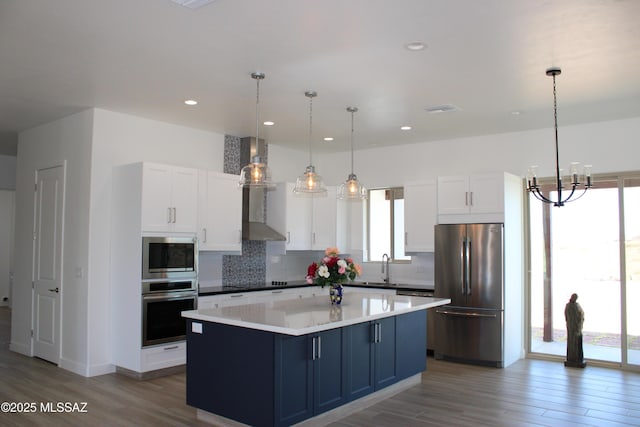 kitchen with stainless steel appliances, white cabinets, light countertops, a center island, and pendant lighting