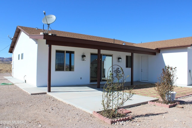 ranch-style home with a patio, roof with shingles, and stucco siding