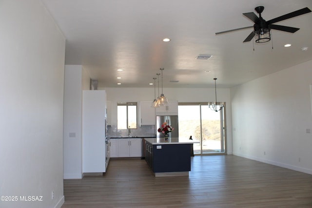 kitchen featuring white cabinets, open floor plan, hanging light fixtures, a center island, and stainless steel fridge