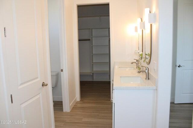 hall featuring light wood finished floors, baseboards, and a sink