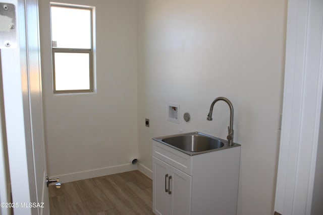 clothes washing area with cabinet space, light wood-style flooring, hookup for a washing machine, hookup for an electric dryer, and a sink