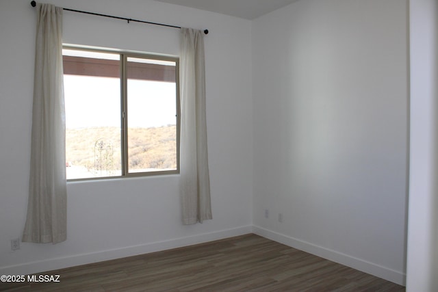 unfurnished room featuring baseboards and wood finished floors