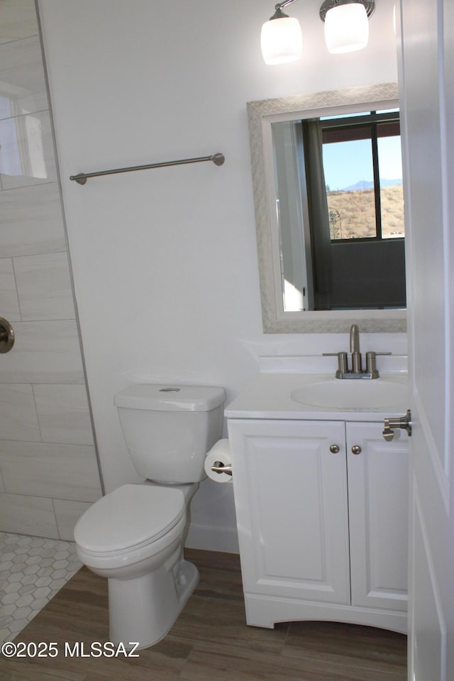 bathroom featuring toilet, a tile shower, and vanity