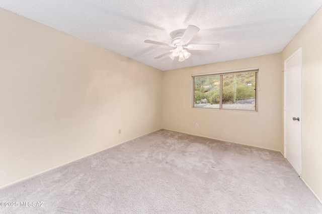 empty room with a ceiling fan, a textured ceiling, and light colored carpet