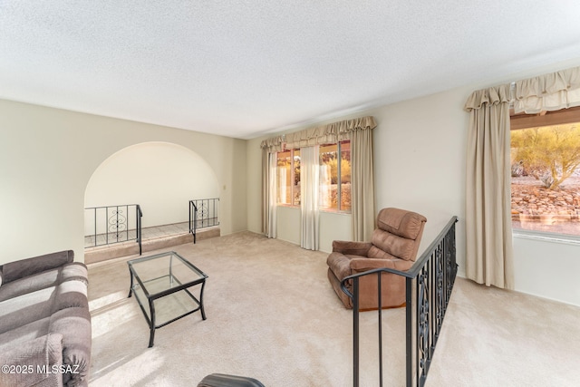 living room with a textured ceiling, carpet, and arched walkways