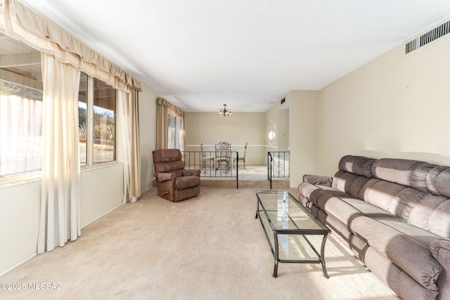 living room featuring a notable chandelier, visible vents, and light colored carpet