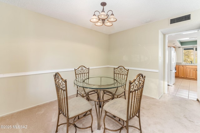 dining area featuring light tile patterned floors, visible vents, a notable chandelier, and light colored carpet