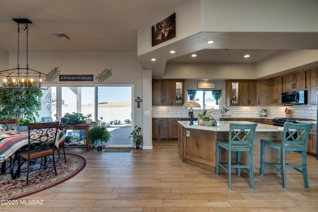 16 Star View Dr, Sonoita, AZ 85637 - kitchen featuring stainless steel microwave, light wood-style flooring, a chandelier, glass insert cabinets, and a center island