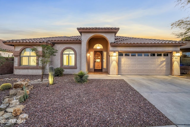 mediterranean / spanish house with a garage, concrete driveway, and stucco siding