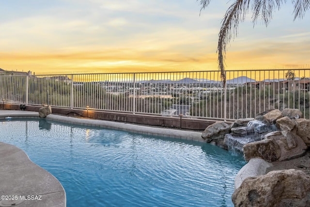 pool at dusk featuring fence and a fenced in pool