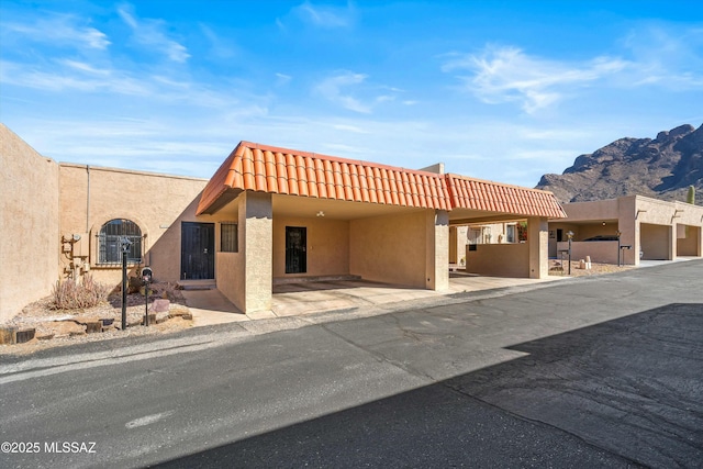 view of front of home with a mountain view, a carport, a tiled roof, and stucco siding