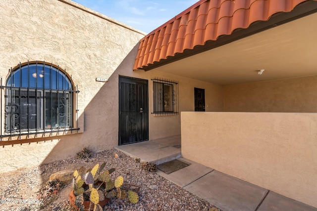 doorway to property with a tile roof and stucco siding