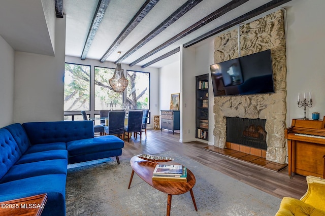 living room featuring a stone fireplace, beamed ceiling, wood finished floors, and baseboards