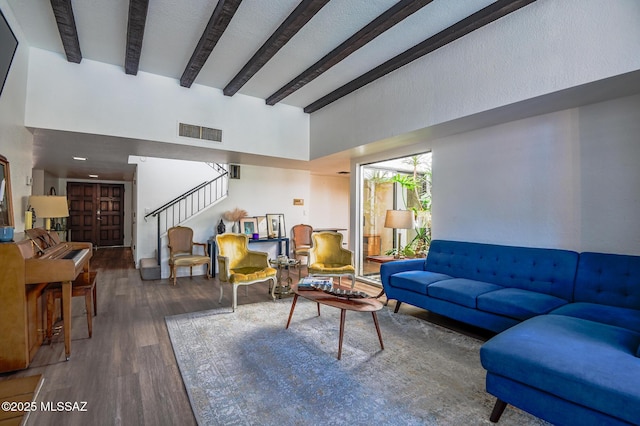 living room with stairway, visible vents, dark wood-type flooring, and beamed ceiling