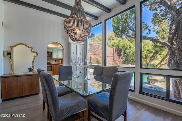 dining area with an inviting chandelier, beam ceiling, arched walkways, and dark wood-type flooring