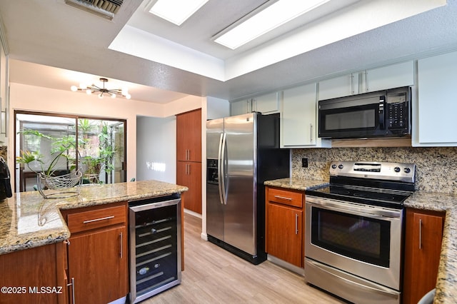 kitchen with light stone counters, beverage cooler, stainless steel appliances, visible vents, and brown cabinetry