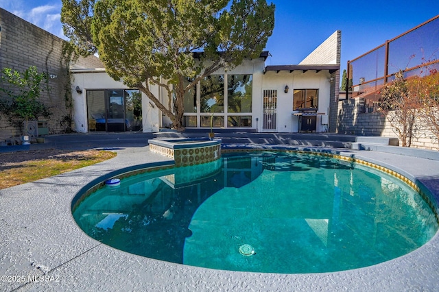 pool with fence and an in ground hot tub