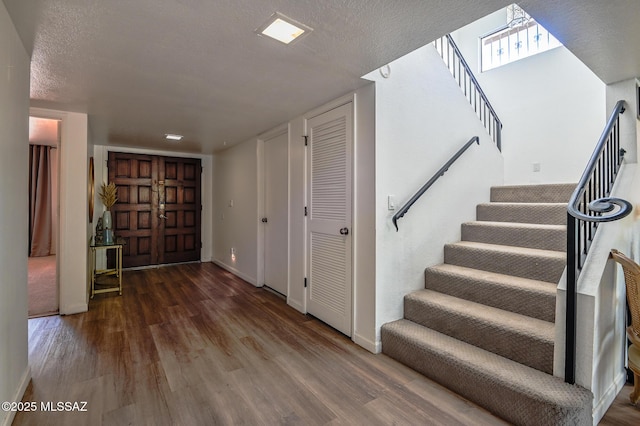 interior space with a textured ceiling, baseboards, and wood finished floors