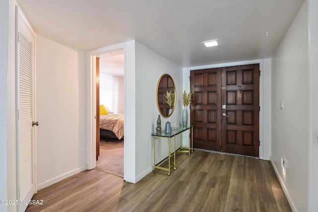 foyer entrance featuring a textured ceiling, wood finished floors, and baseboards