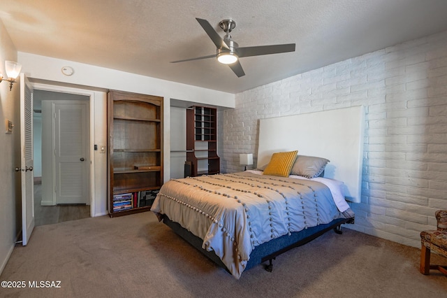 bedroom with a textured ceiling, brick wall, ceiling fan, and carpet