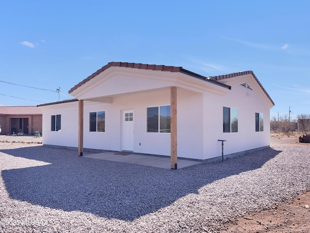 rear view of house featuring a tile roof, a patio, and stucco siding