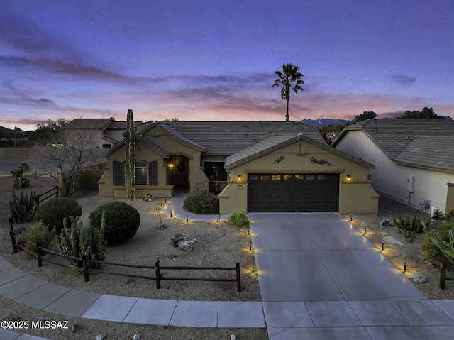 view of front facade featuring driveway, a fenced front yard, an attached garage, and stucco siding