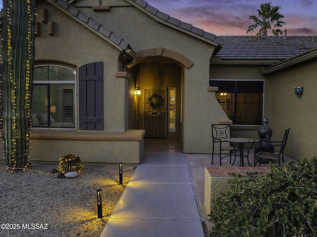 view of exterior entry featuring a tiled roof and stucco siding