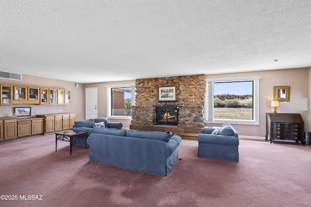 living room featuring light carpet, a fireplace, visible vents, and a textured ceiling