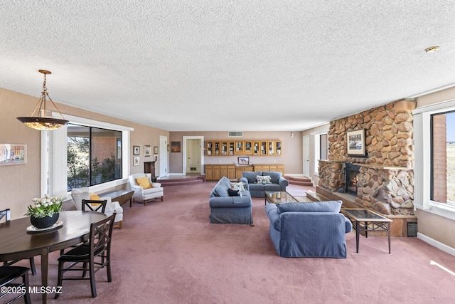 carpeted living room featuring a textured ceiling, plenty of natural light, a fireplace, and visible vents