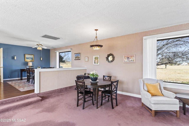 carpeted dining area featuring a ceiling fan, baseboards, visible vents, and a textured ceiling