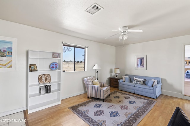 living area with baseboards, ceiling fan, visible vents, and wood finished floors