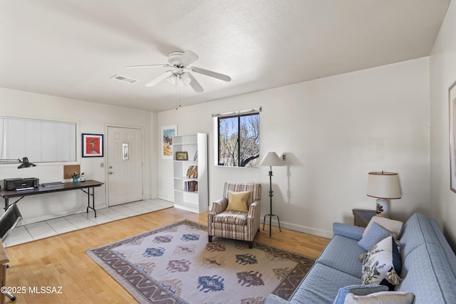 living area featuring visible vents, ceiling fan, baseboards, and wood finished floors