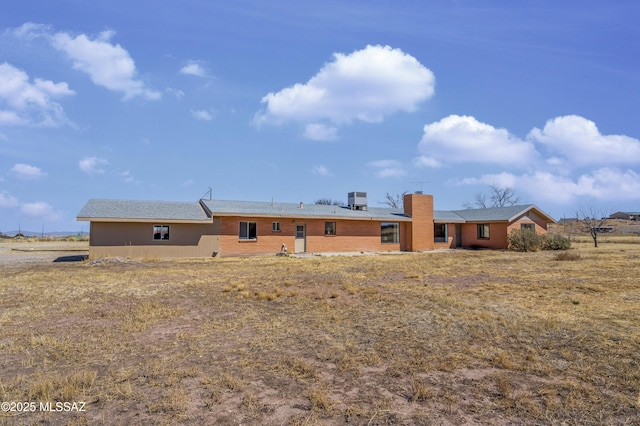 rear view of house featuring cooling unit and a chimney