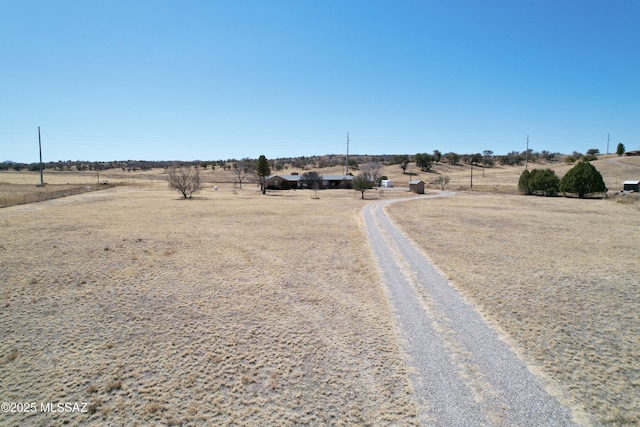 view of street with a rural view and gravel driveway