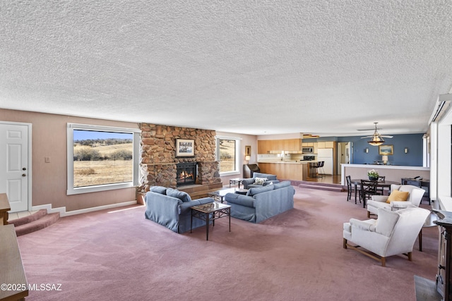 living room featuring carpet, baseboards, a stone fireplace, and a textured ceiling