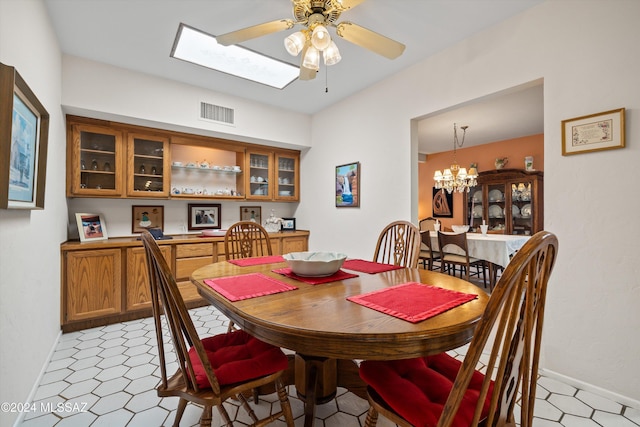 dining space with ceiling fan with notable chandelier, light floors, visible vents, and baseboards