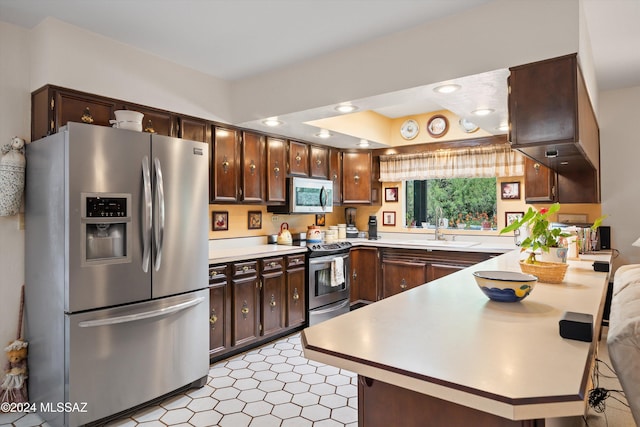 kitchen with appliances with stainless steel finishes, light countertops, a sink, and light floors