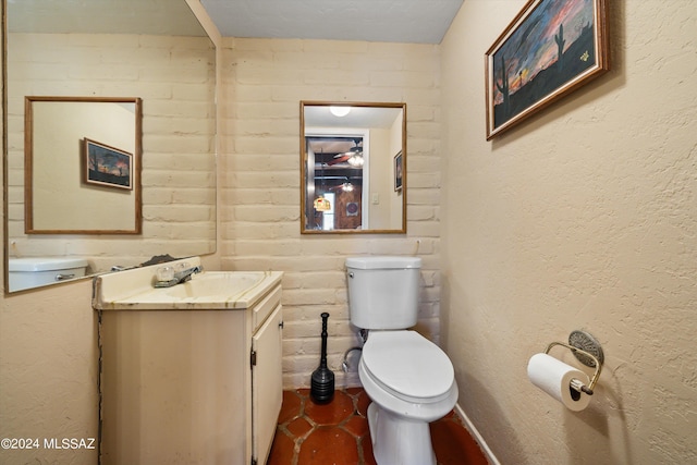 bathroom featuring toilet, a textured wall, and vanity