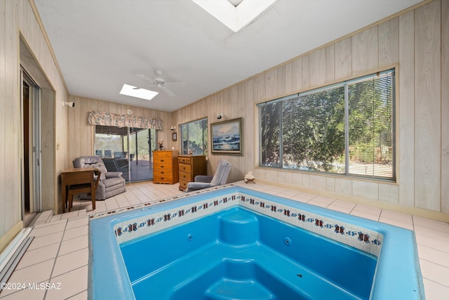 view of pool with a skylight, ceiling fan, and a hot tub