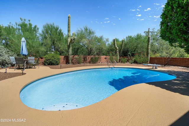 view of swimming pool featuring a fenced backyard, a diving board, a fenced in pool, and a patio