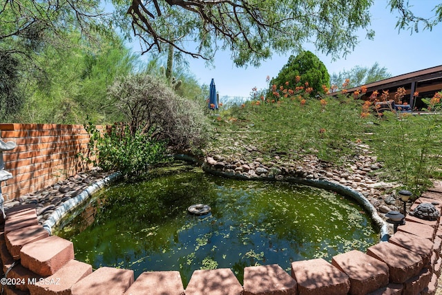 view of pool featuring fence and a garden pond