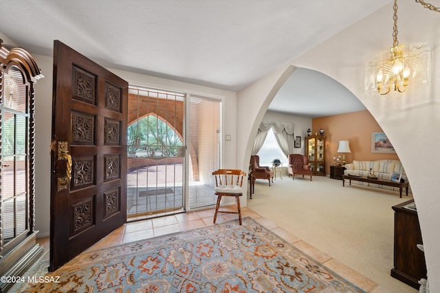 entrance foyer with a chandelier, arched walkways, a wealth of natural light, and light carpet