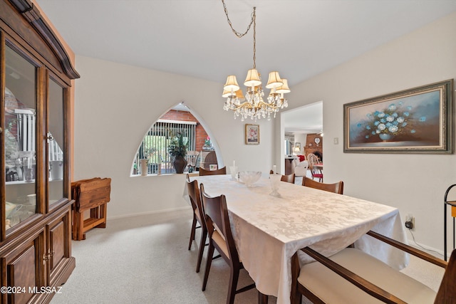 dining space featuring arched walkways, light carpet, a notable chandelier, and baseboards