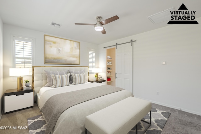 carpeted bedroom featuring a ceiling fan, visible vents, baseboards, and a barn door