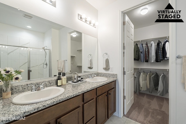 bathroom with a spacious closet, double vanity, a sink, and a shower stall