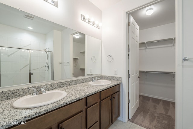 bathroom featuring double vanity, a sink, a walk in closet, and a shower stall