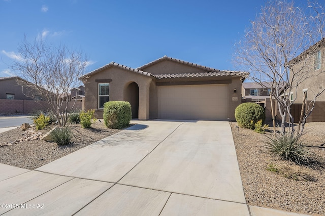 mediterranean / spanish-style house featuring stucco siding, concrete driveway, an attached garage, fence, and a tiled roof