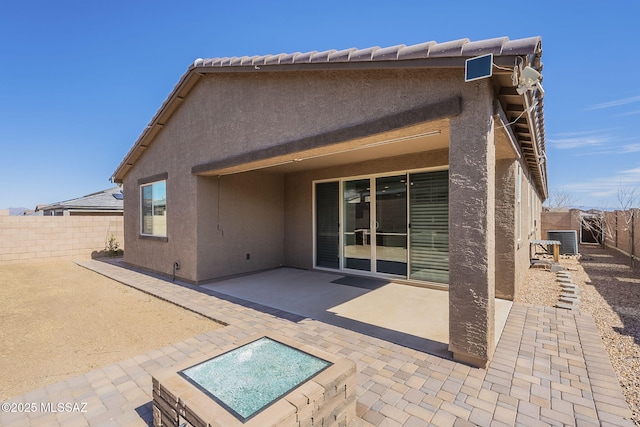 rear view of property featuring stucco siding, a fenced backyard, central AC, and a patio